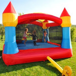 Children playing on a colorful inflatable bounce house in a grassy area.
