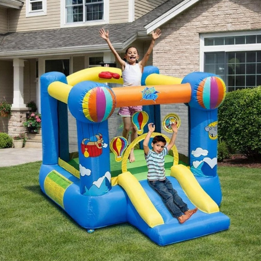 Children playing on a colorful inflatable bounce house in front of a house.