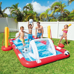 Children playing with an inflatable pool and sports set on a grassy area with palm trees in the background.