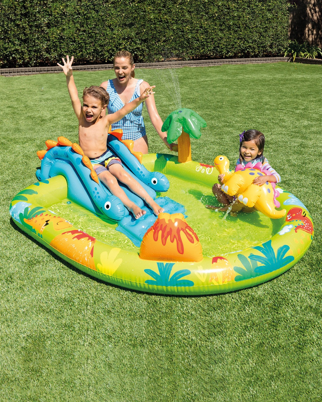 Children playing on an inflatable water play center in a grassy area.