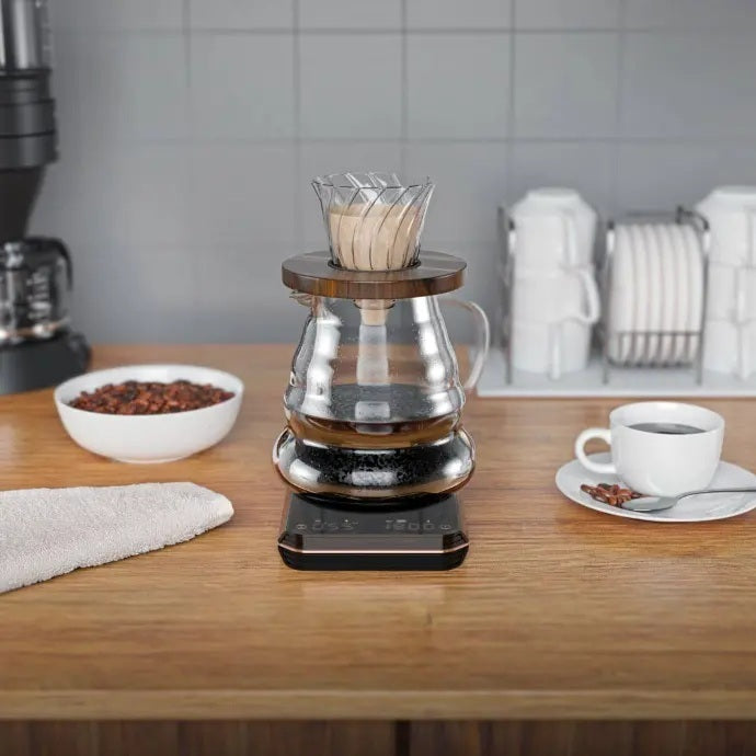 Coffee brewing setup on a kitchen counter with a bowl of coffee beans and a cup of coffee.