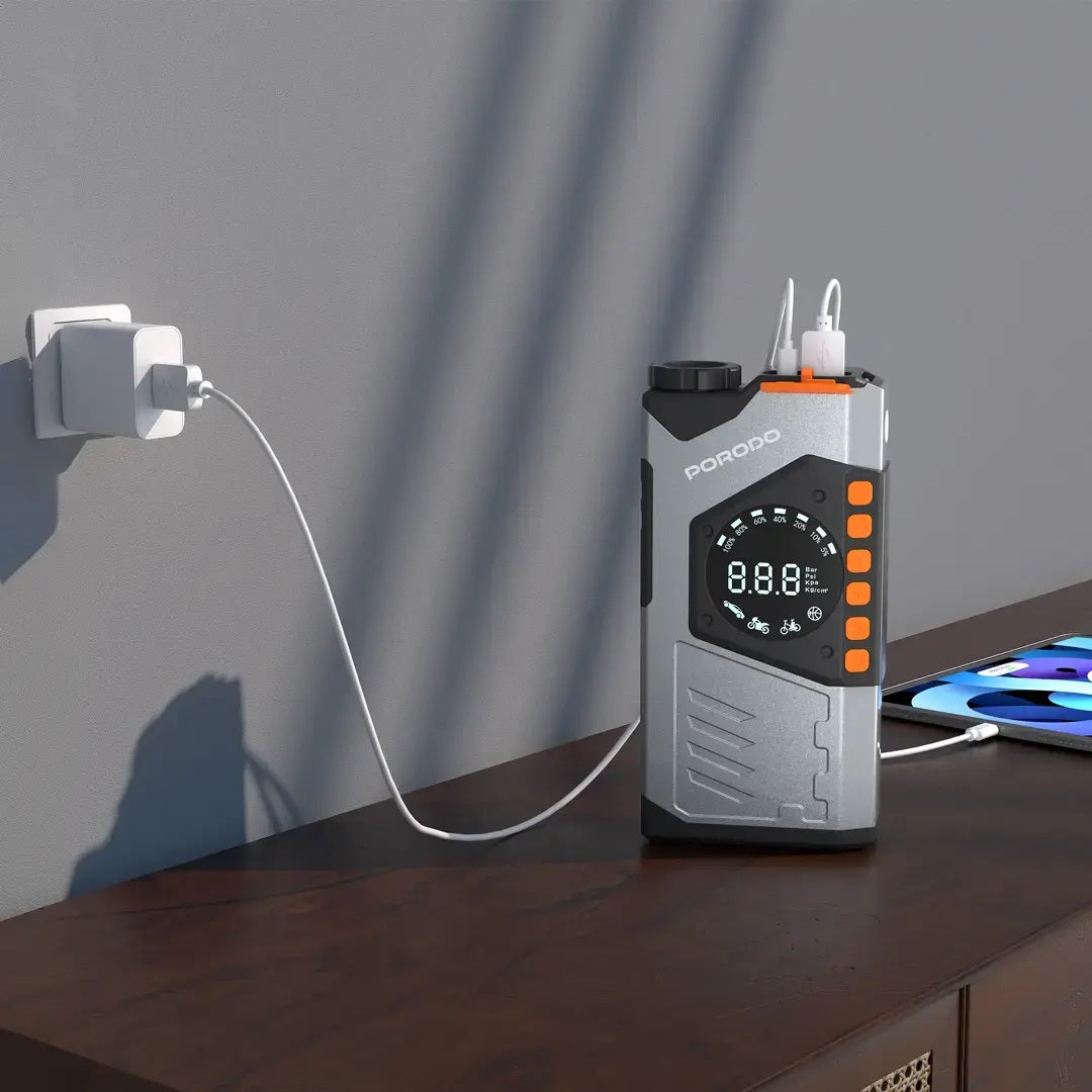 Portable power station with digital display on a wooden surface, plugged into an outlet.