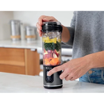 Person using a Ninja blender with ingredients inside on a kitchen counter