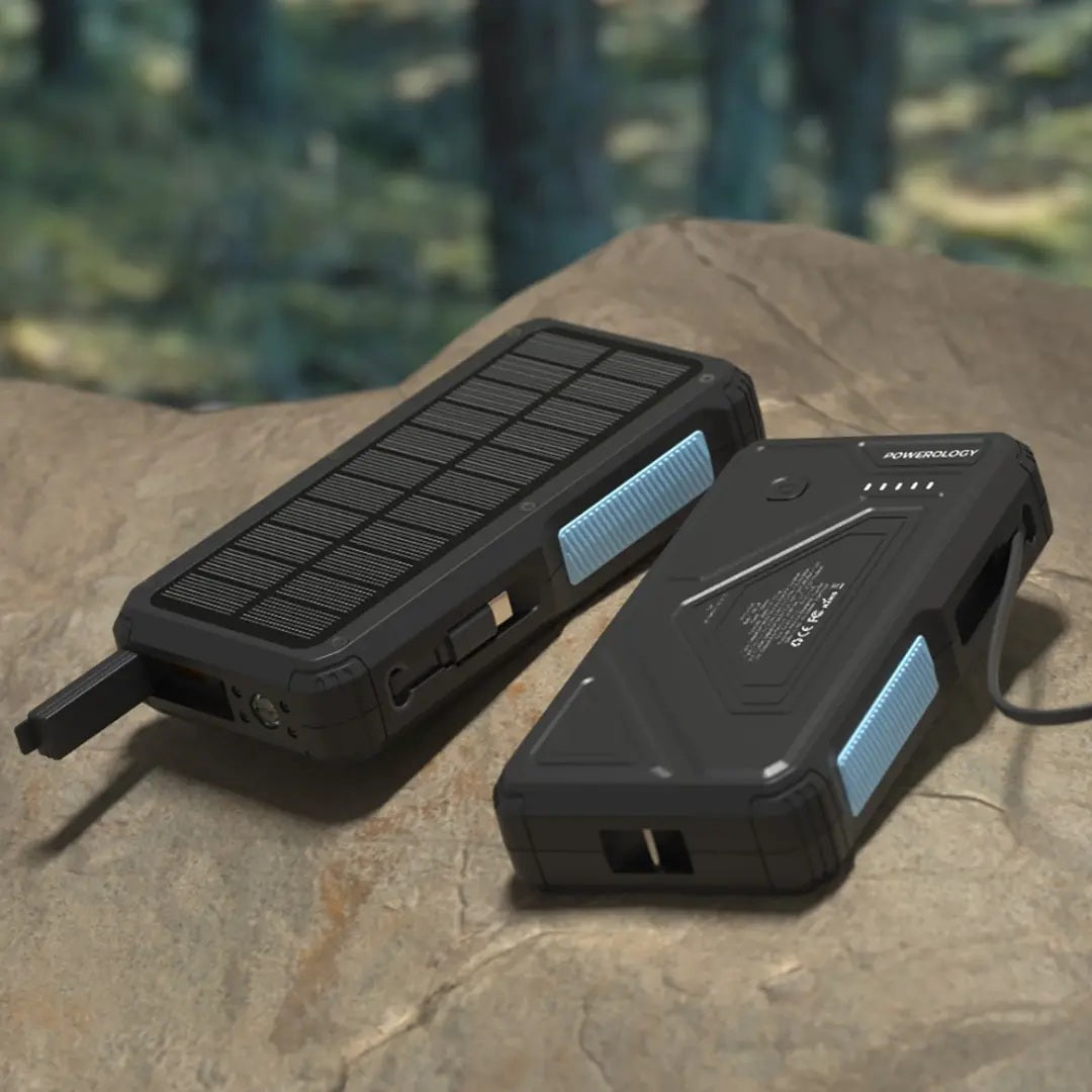 Two black portable power stations with solar panels on a stone surface.