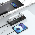 Power strip with multiple outlets and USB ports on a desk with two electronic devices.