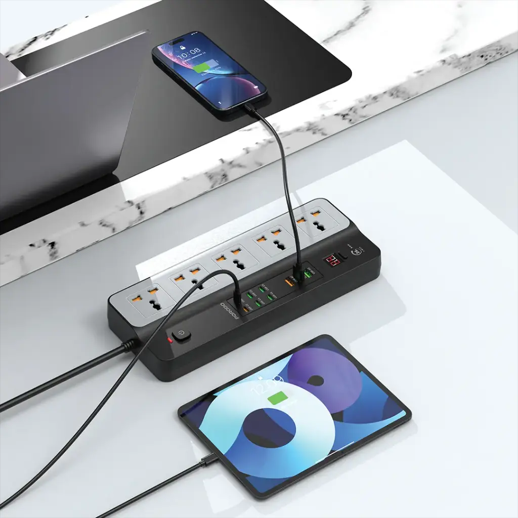 Power strip with multiple outlets and USB ports on a desk with two electronic devices.