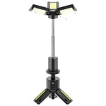 Black Green Lion Trio Beam Camping Light on tripod, extended, illuminating a dark campsite.