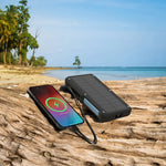 Solar phone charger on a beach with ocean and trees in the background