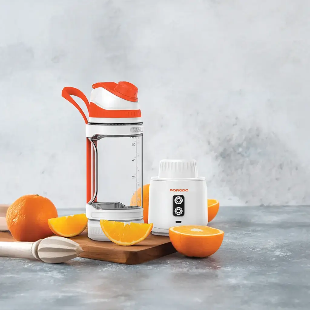 Orange-themed kitchen items including a blender and juicer on a gray surface with oranges.