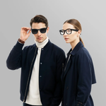 Man and woman wearing dark sunglasses against a gray background