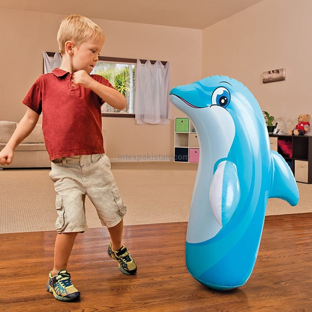 Child playing with an inflatable dolphin toy in a room.