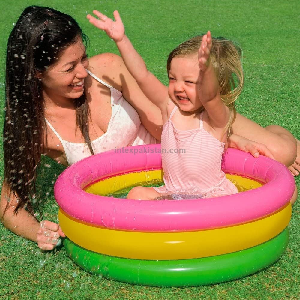 Woman and child playing in a colorful inflatable pool on grass