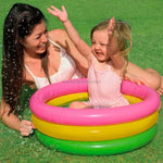 Woman and child playing in a colorful inflatable pool on grass