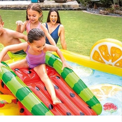 Children playing on a colorful inflatable pool toy shaped like watermelon slices in a garden.