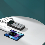 Power strip with multiple outlets and a smartphone on a white surface with a teal background