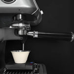 Espresso machine brewing a shot of coffee into a white cup against a black background
