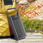 Black power bank with digital display on a wooden surface, person in yellow jacket in background